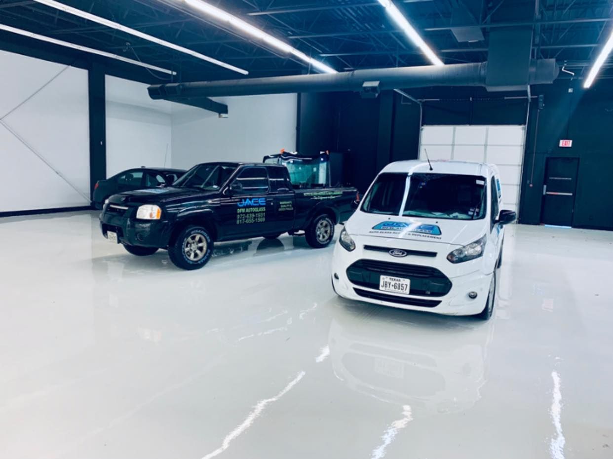 White Ford van and black pickup truck in a clean, modern garage.