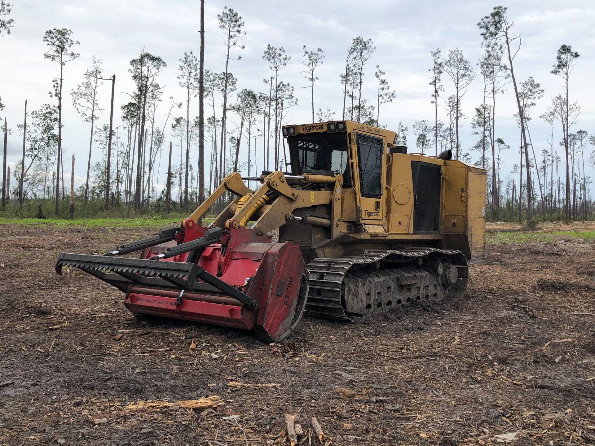 A bulldozer is sitting in a field with trees in the background.