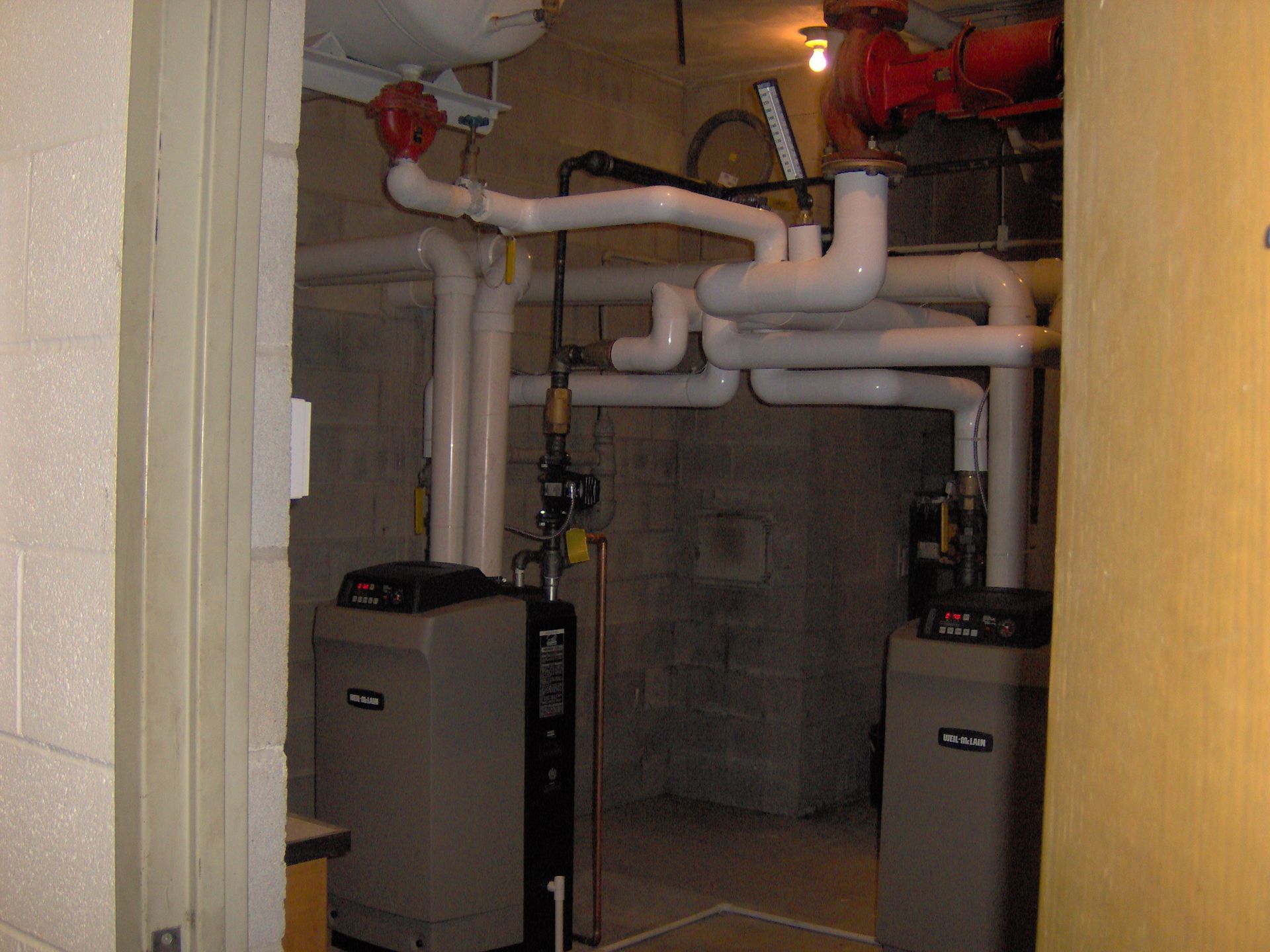 A room filled with pipes and a heater that says carrier on it