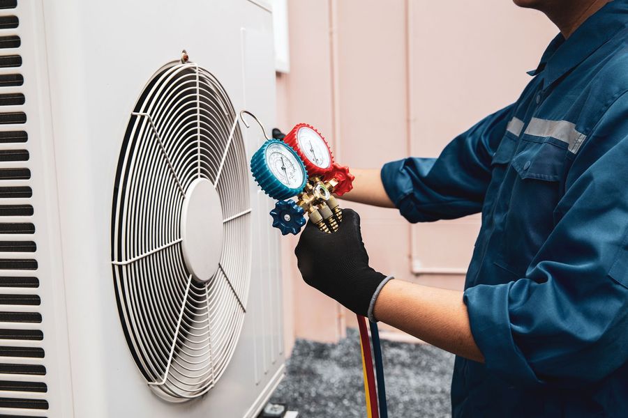 A man is working on an air conditioner outside of a building.