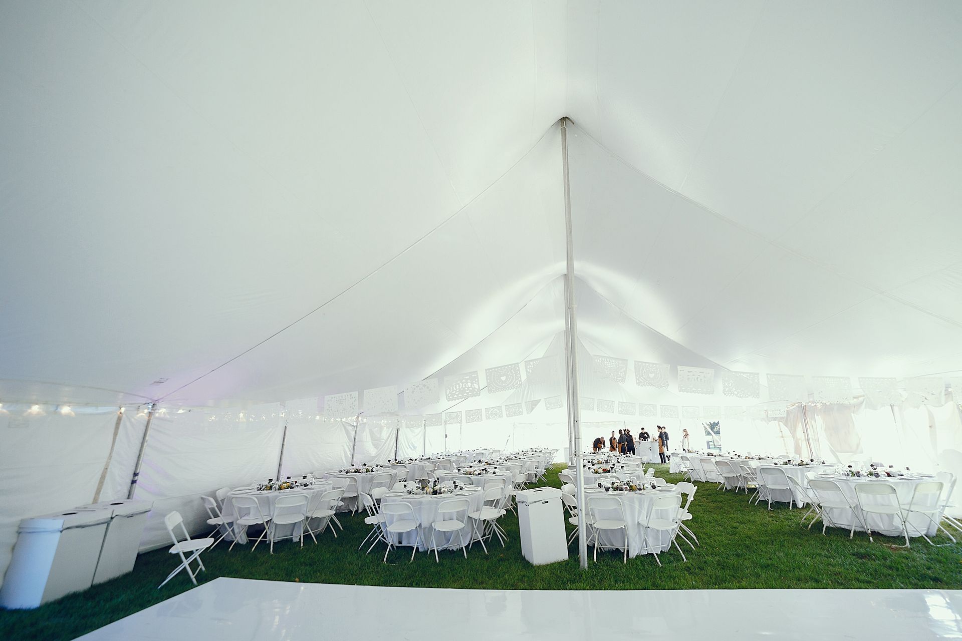 White tent interior with round tables set for a gathering