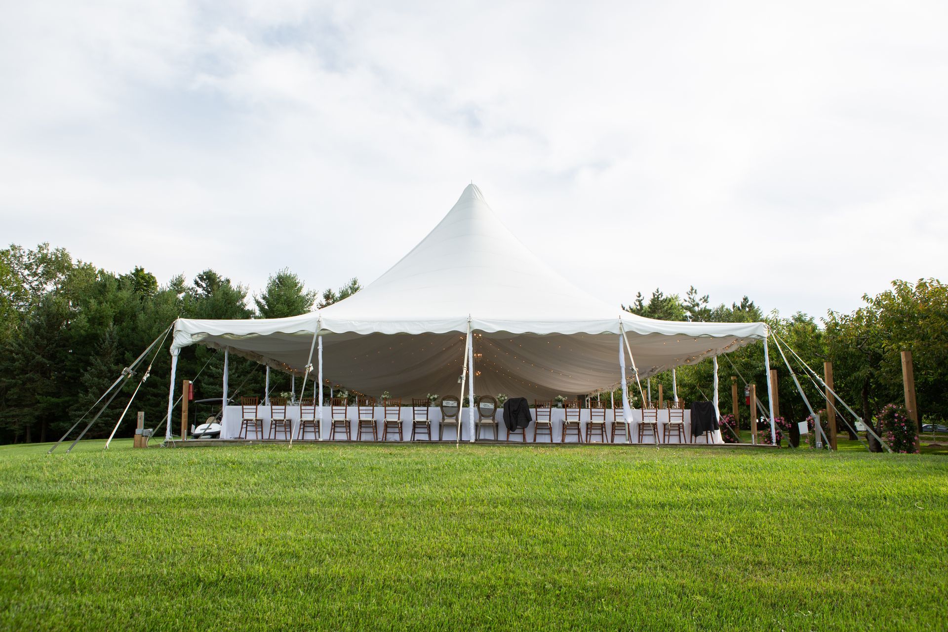 White tent set up on green lawn with tables and chairs