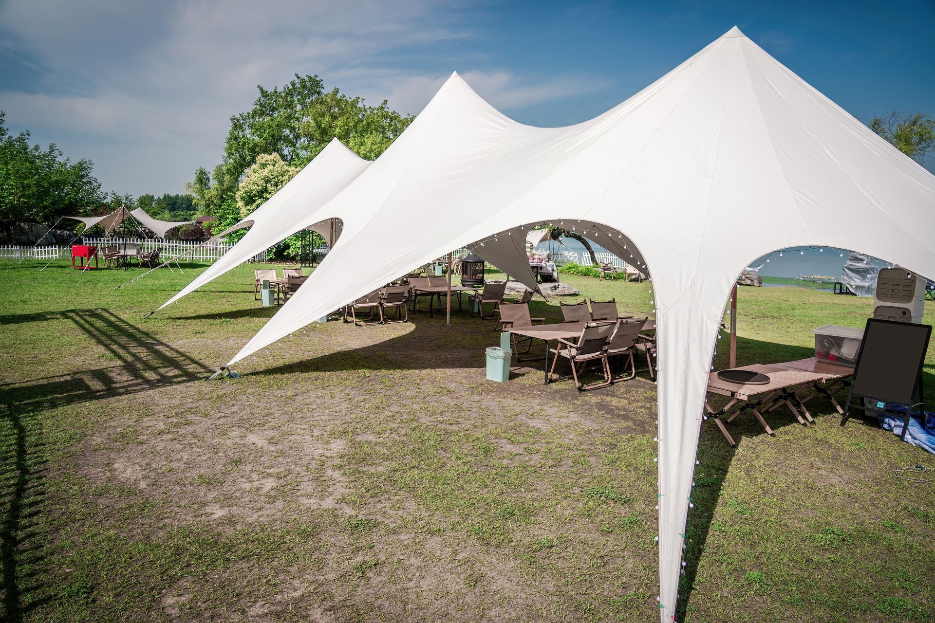 White star-shaped tent set up on a grassy field with tables and chairs for an outdoor event