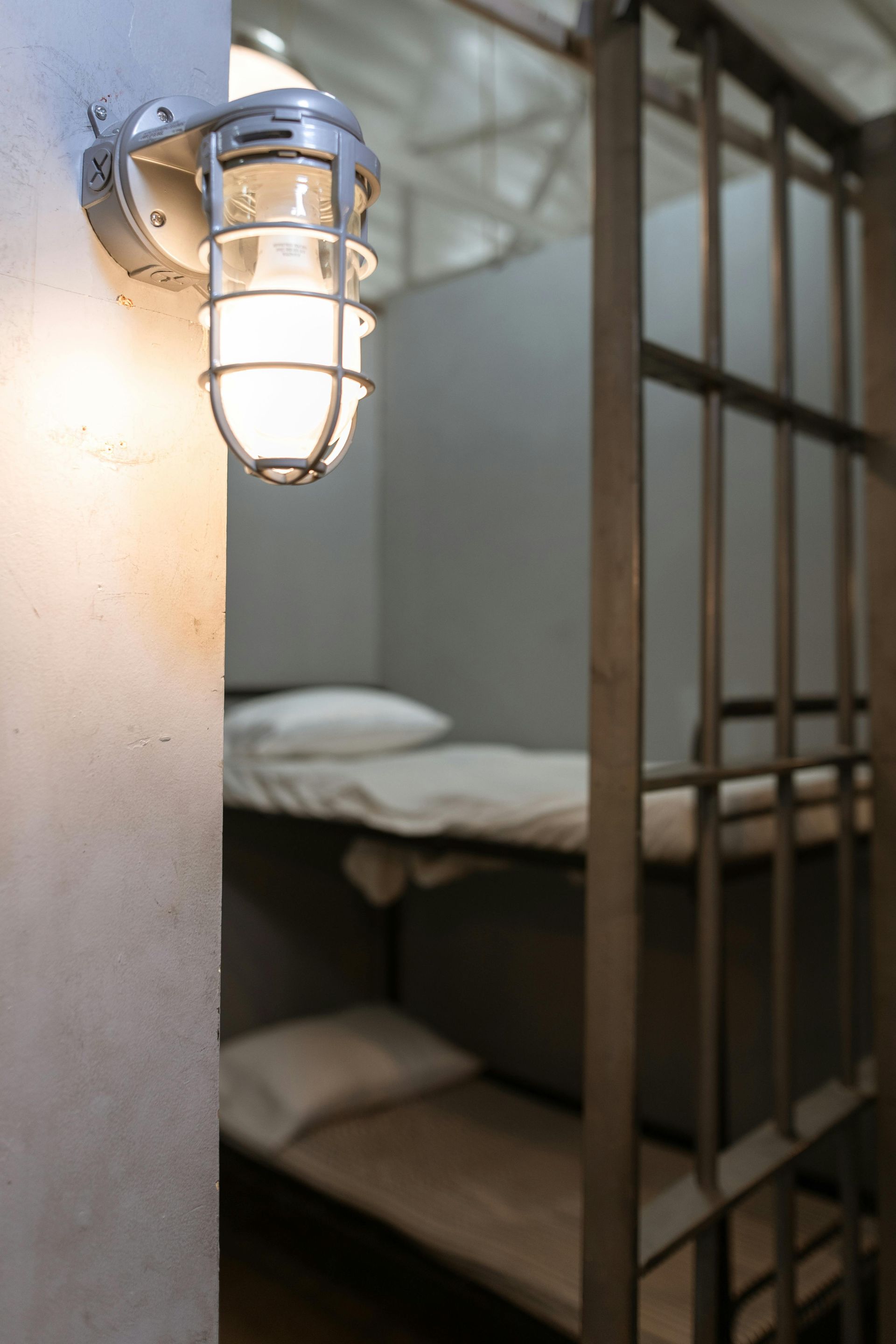 A prison cell with bunk beds and a light on the wall.