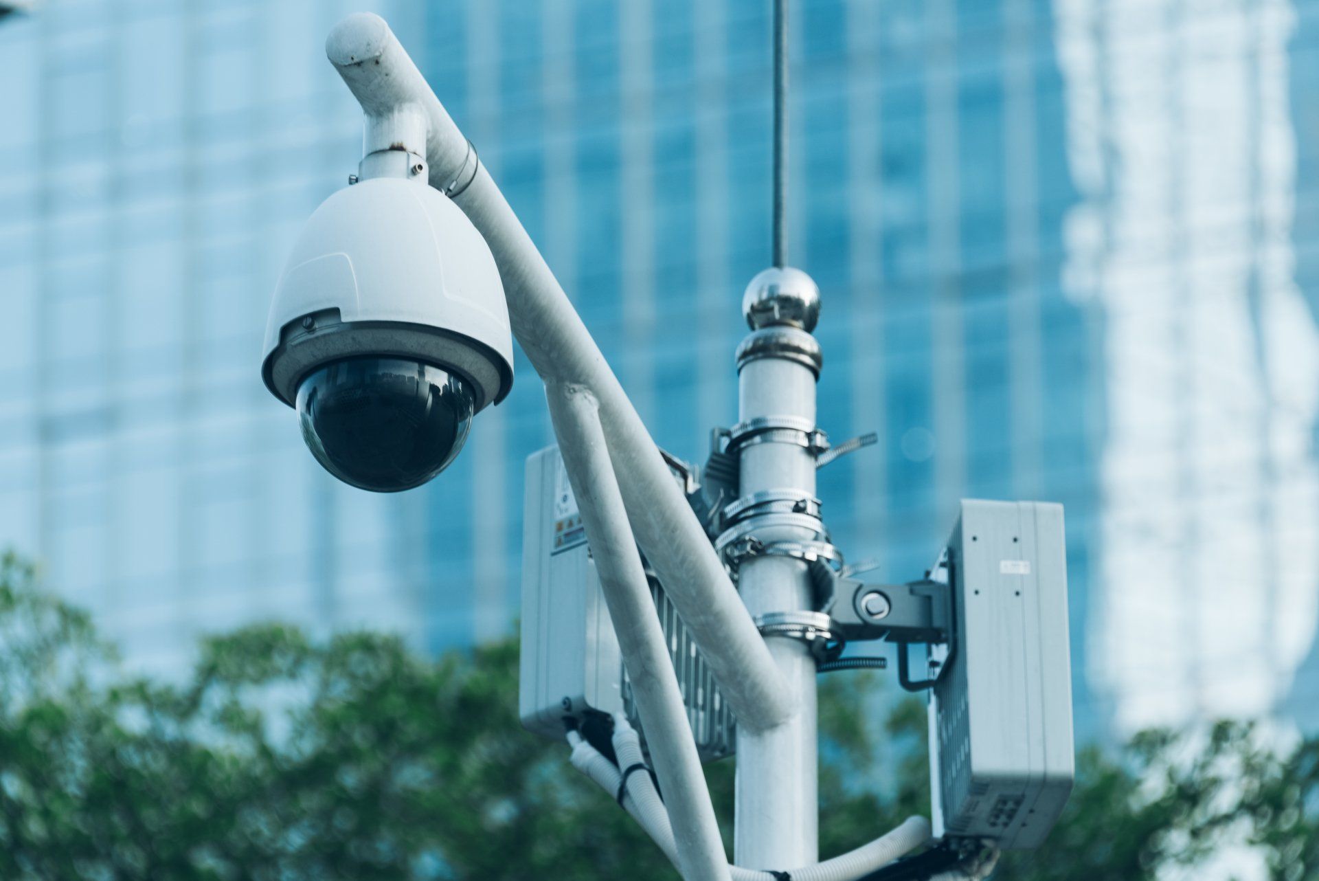 A security camera is sitting on top of a pole in front of a building.