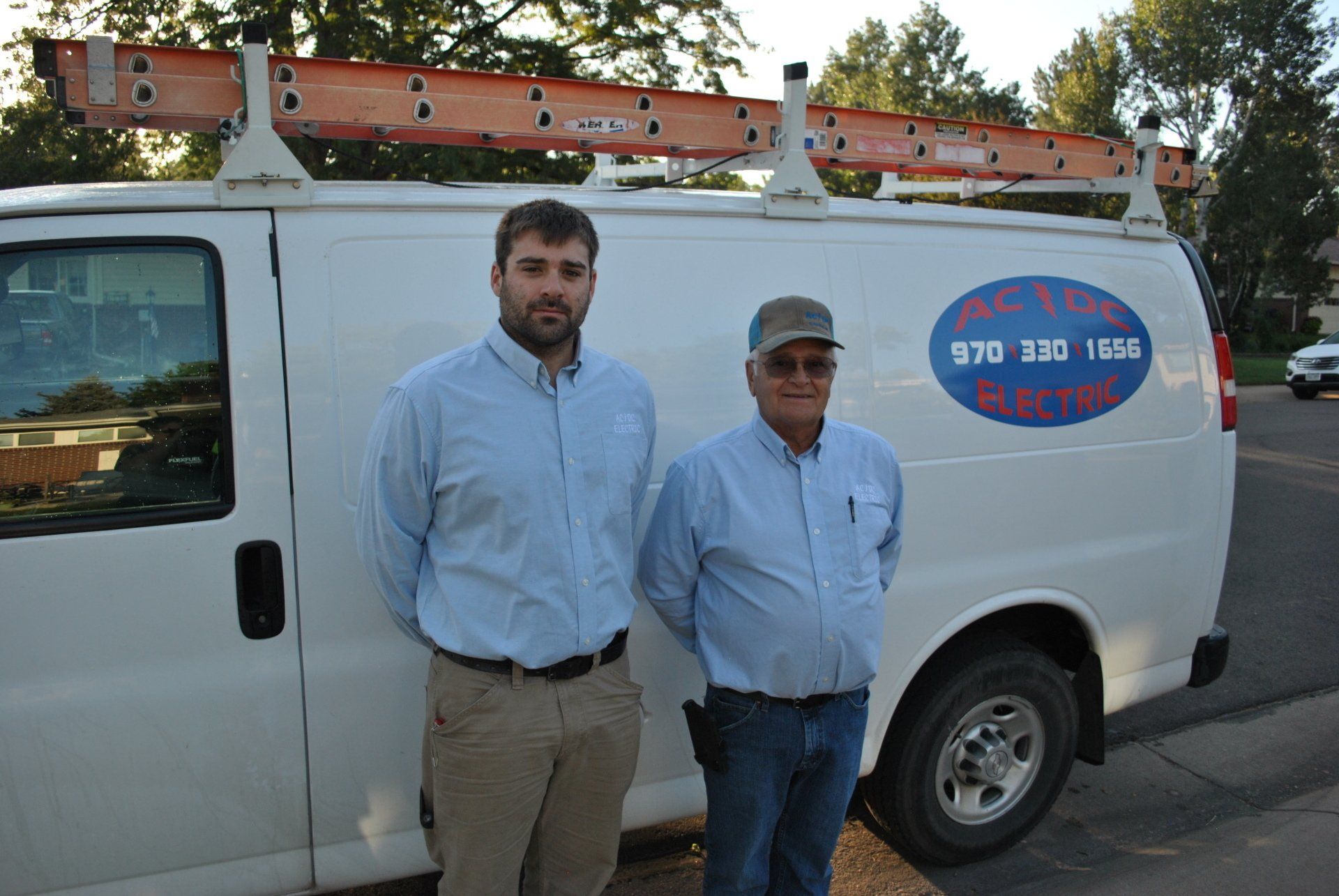 Two men are standing in front of a white van.