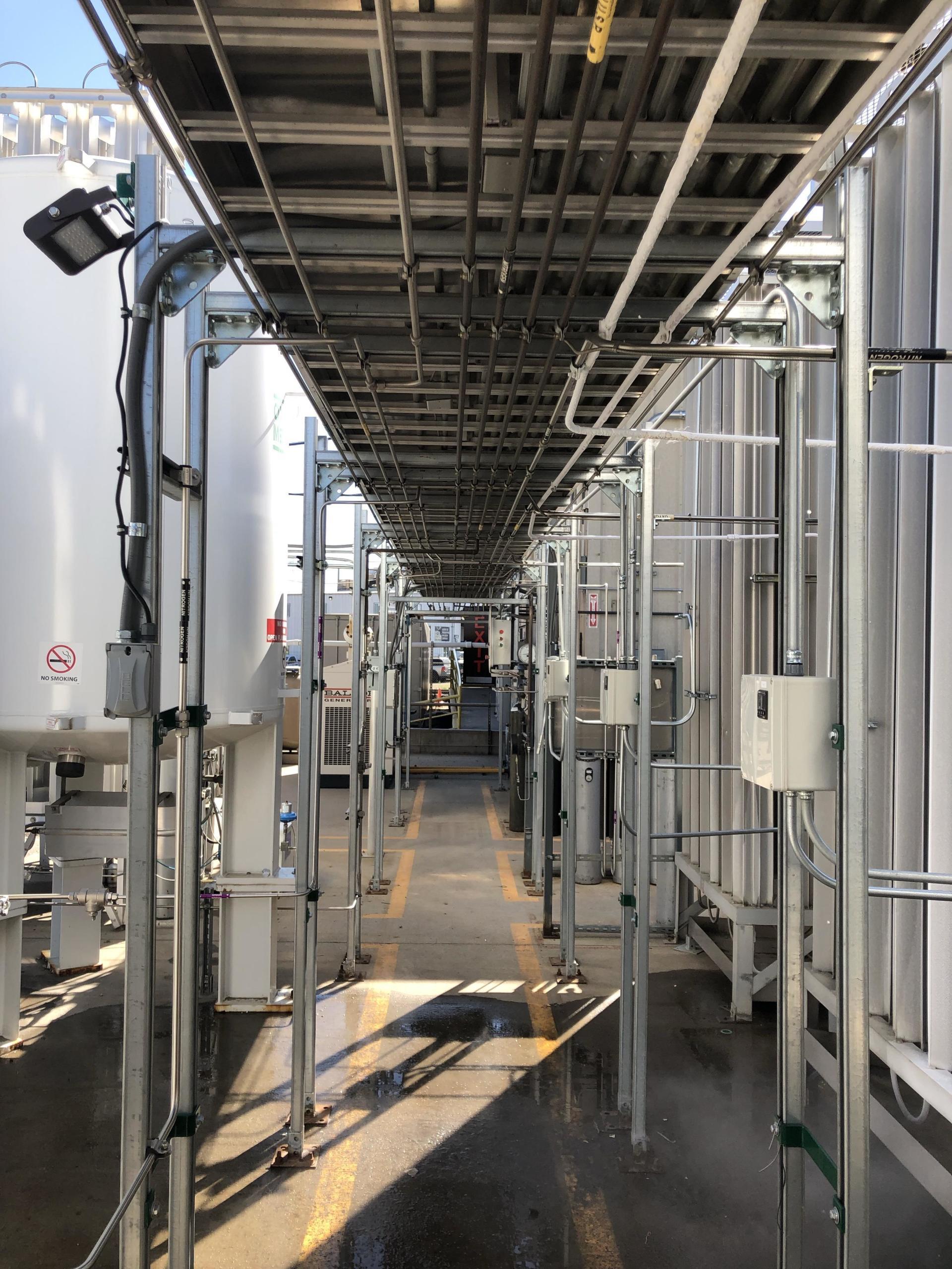 A long hallway in a factory with a lot of pipes