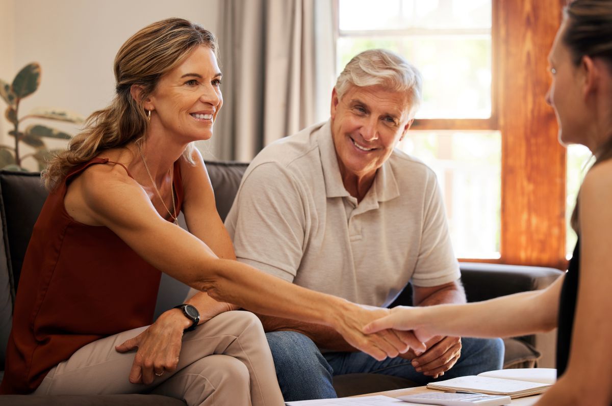 A man and woman are shaking hands with a woman while sitting on a couch.