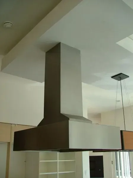 A stainless steel hood is hanging from the ceiling in a kitchen