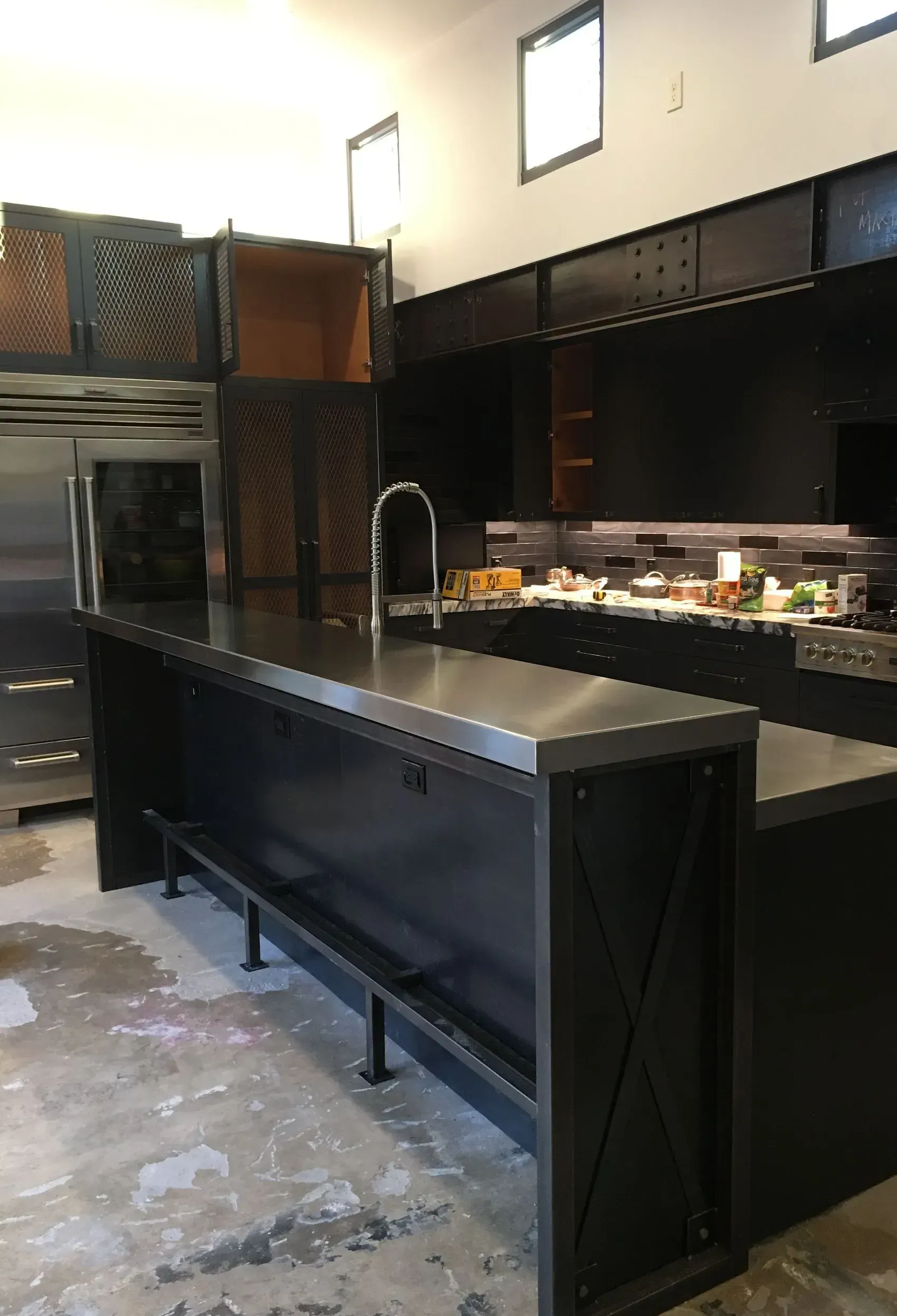 A kitchen with a large island and stainless steel counter tops.