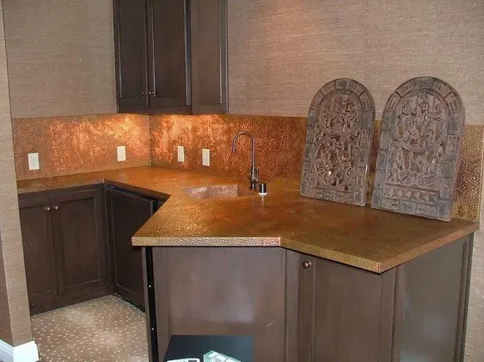 A kitchen with brown cabinets and a copper counter top