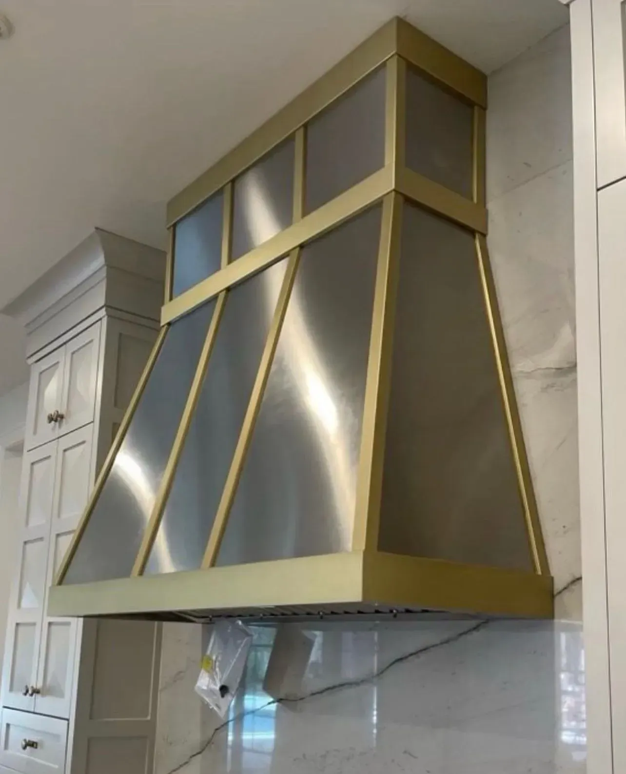 A stainless steel hood is hanging from the ceiling in a kitchen