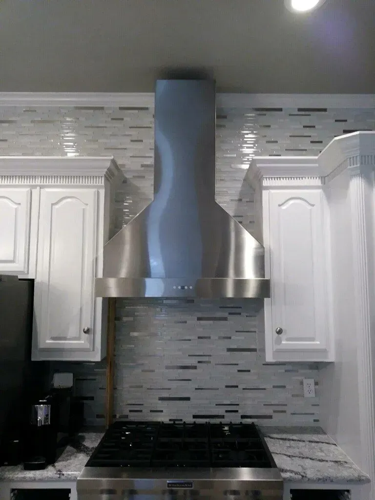 A kitchen with a stove top oven and a stainless steel hood