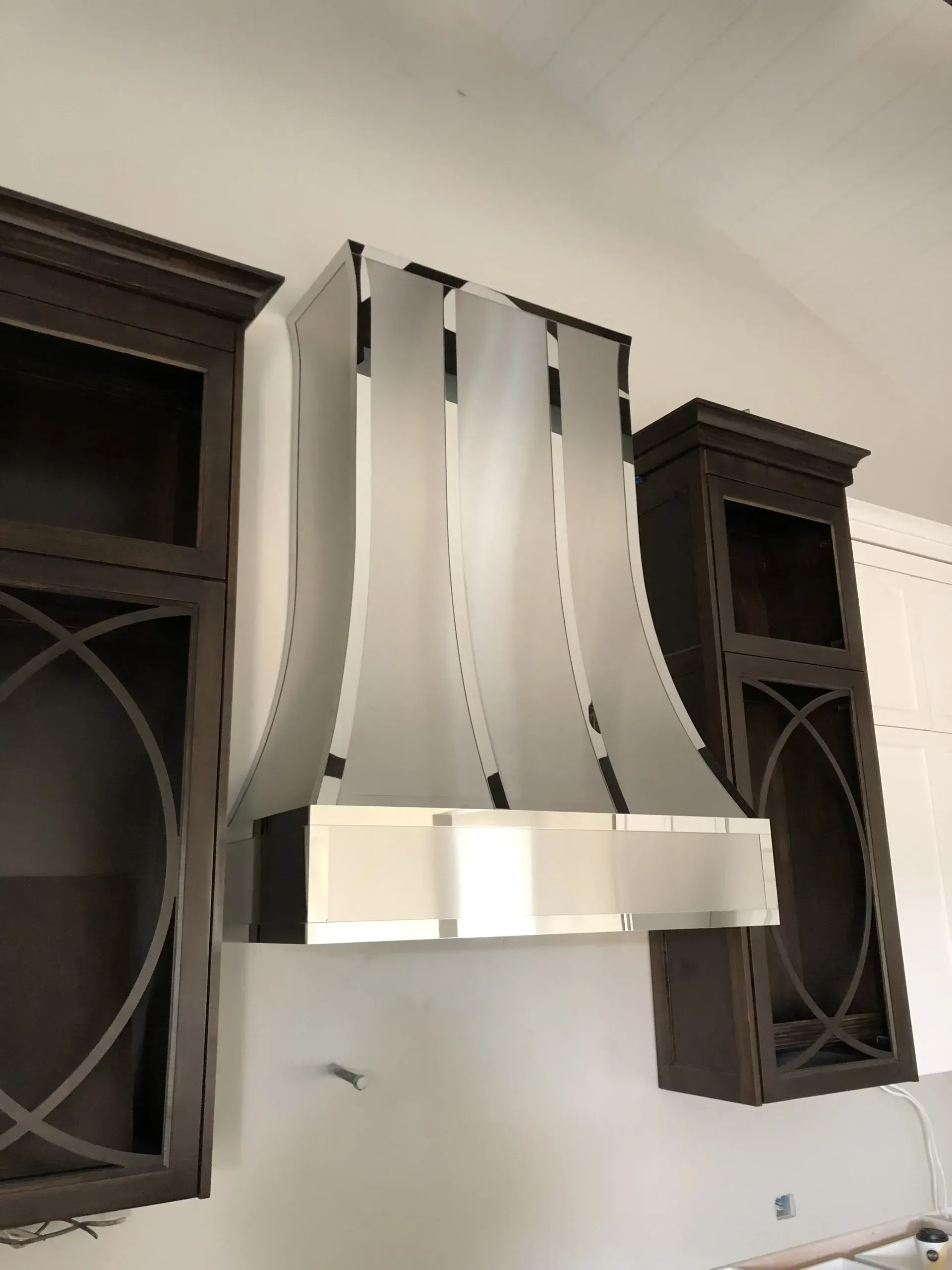 A stainless steel hood is hanging from the ceiling in a kitchen