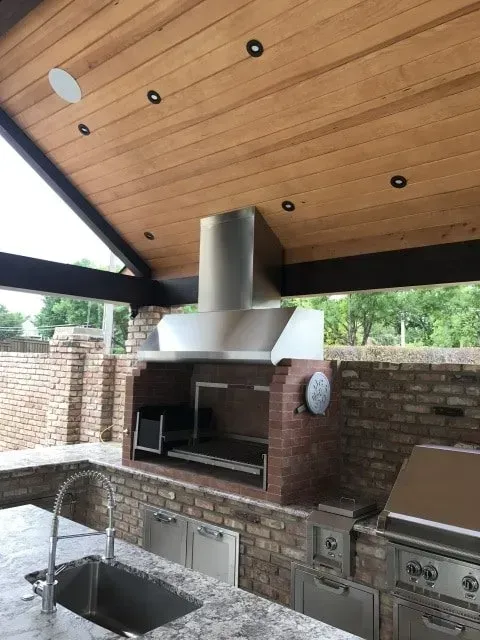 A kitchen with a sink a grill and a wooden ceiling