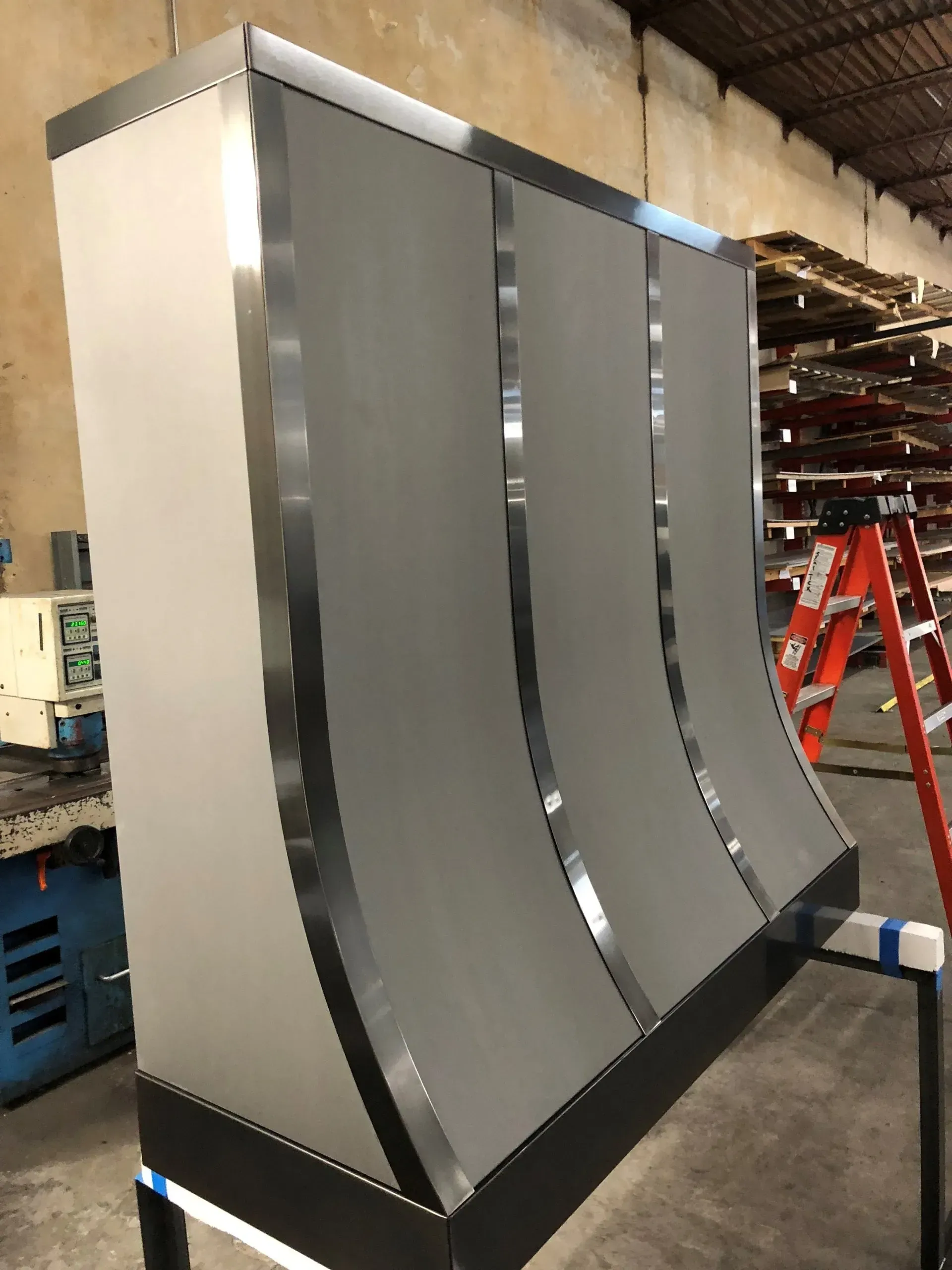 A stainless steel hood is sitting on top of a table in a warehouse.