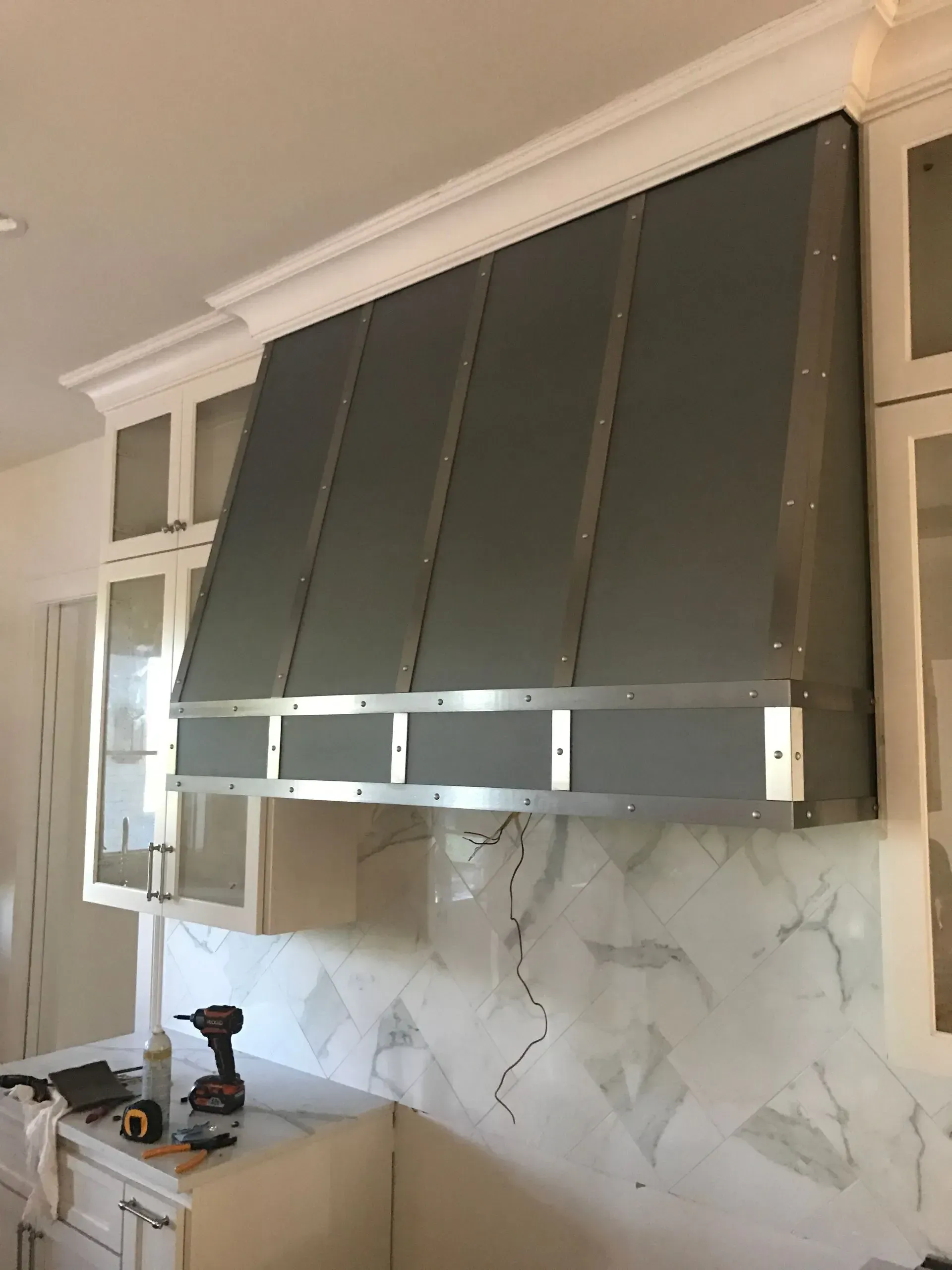 A kitchen with a stainless steel hood hanging from the ceiling.