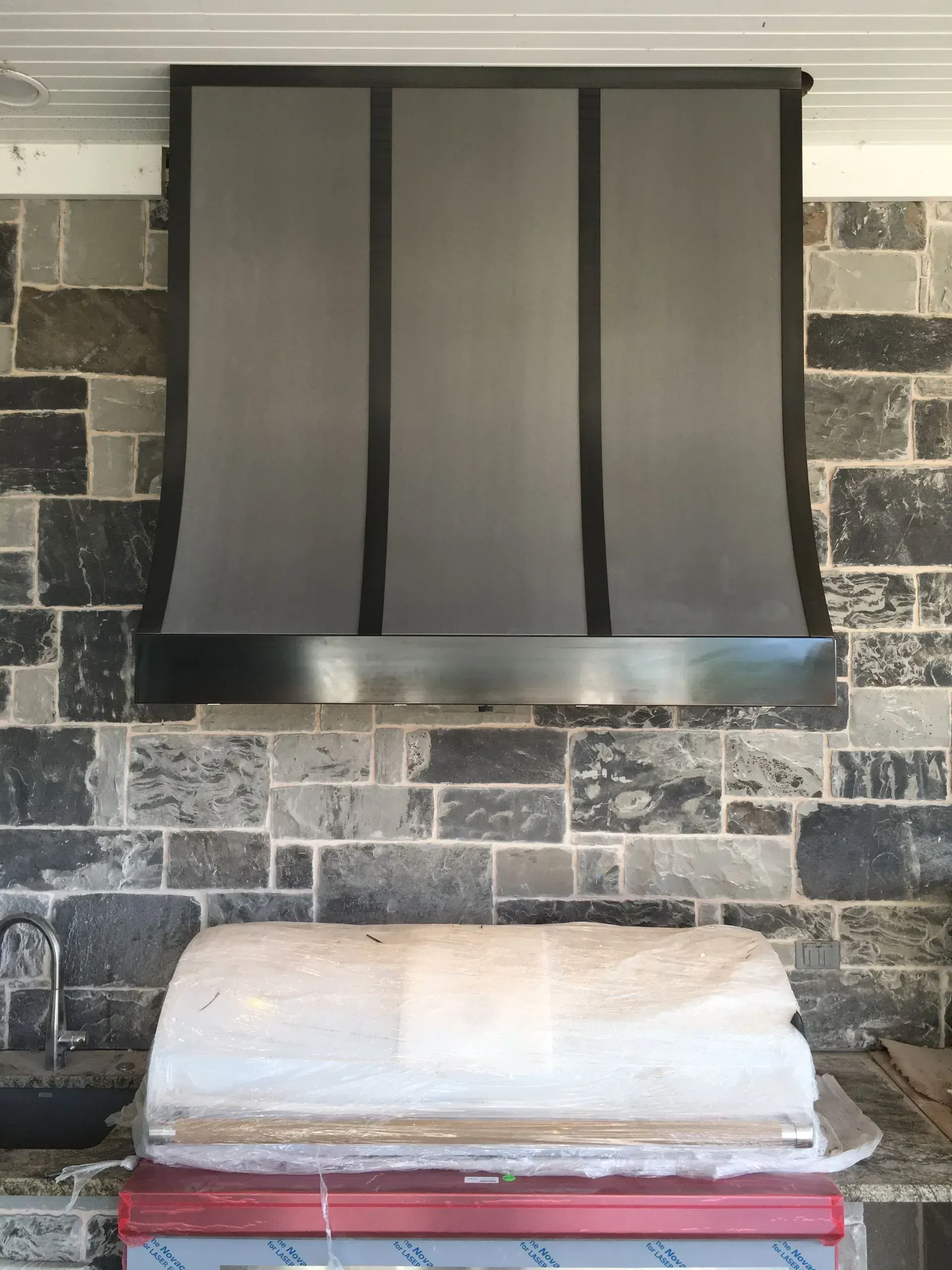 A stainless steel hood is hanging over a brick wall.