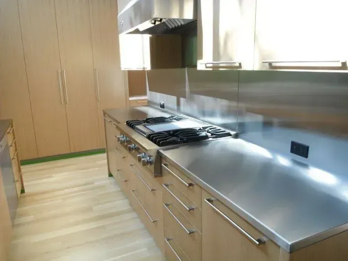 A kitchen with stainless steel counter tops and wooden cabinets