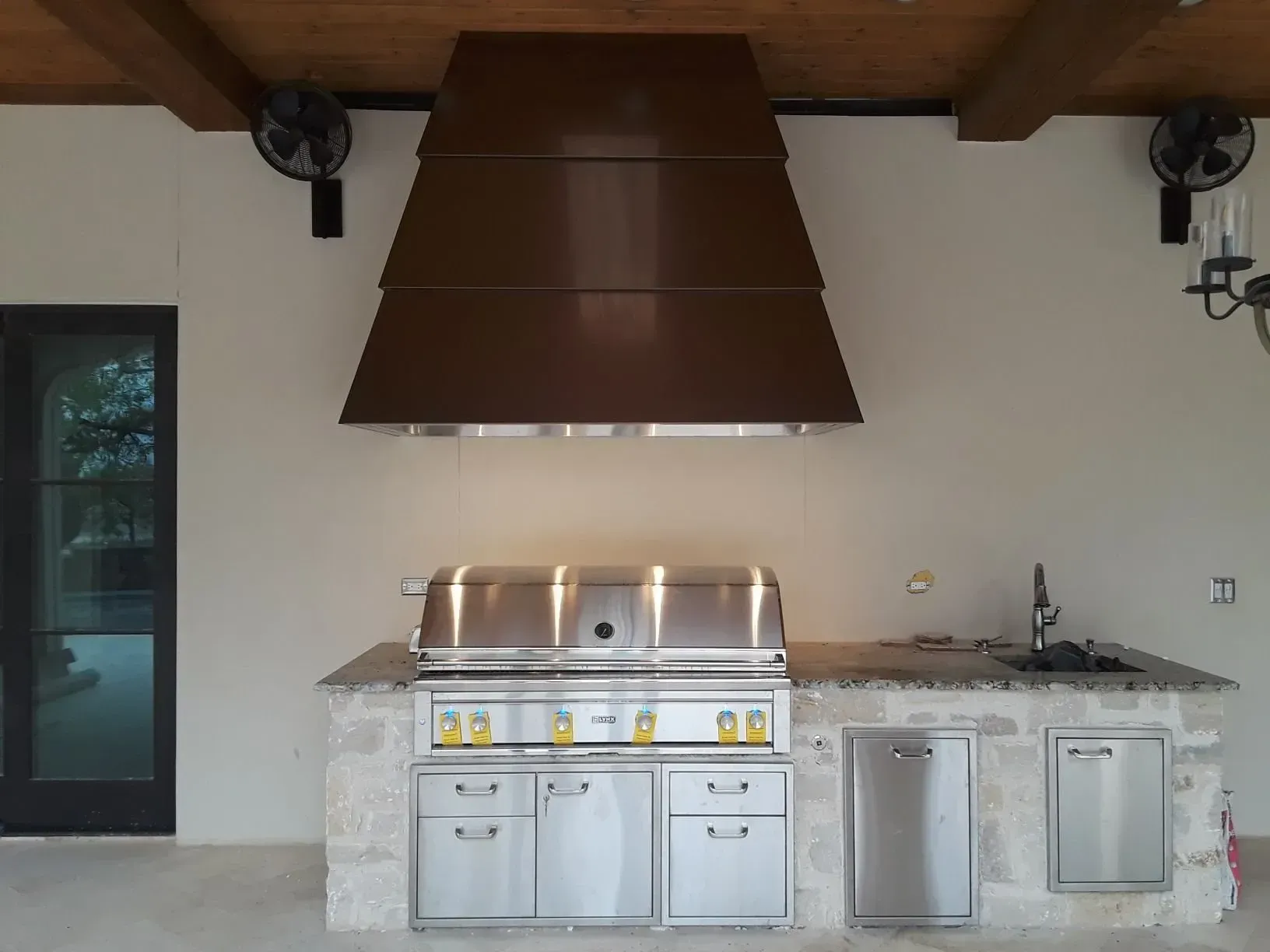 A stainless steel grill with a brown hood above it