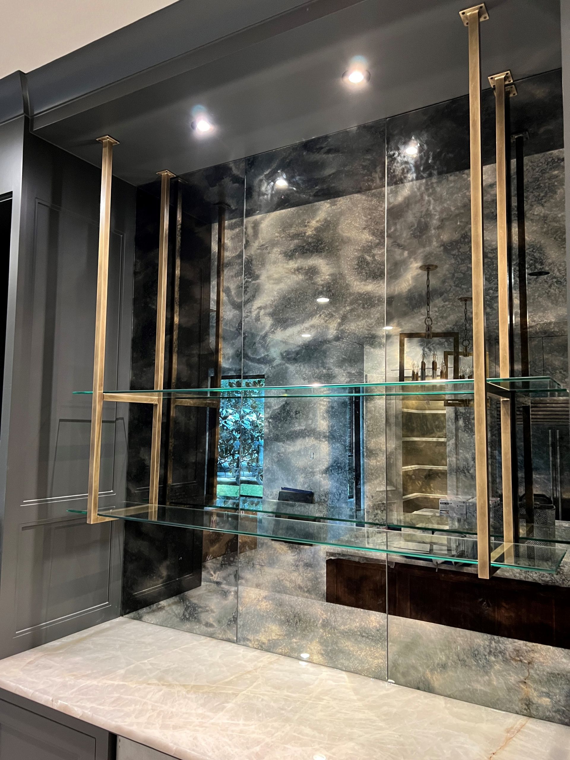 A room with a marble counter top and glass shelves.