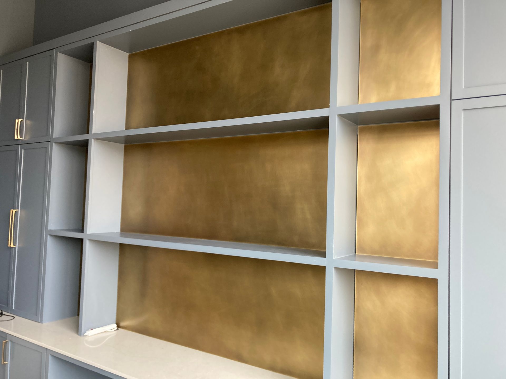 A room with a lot of shelves and a gold wall.