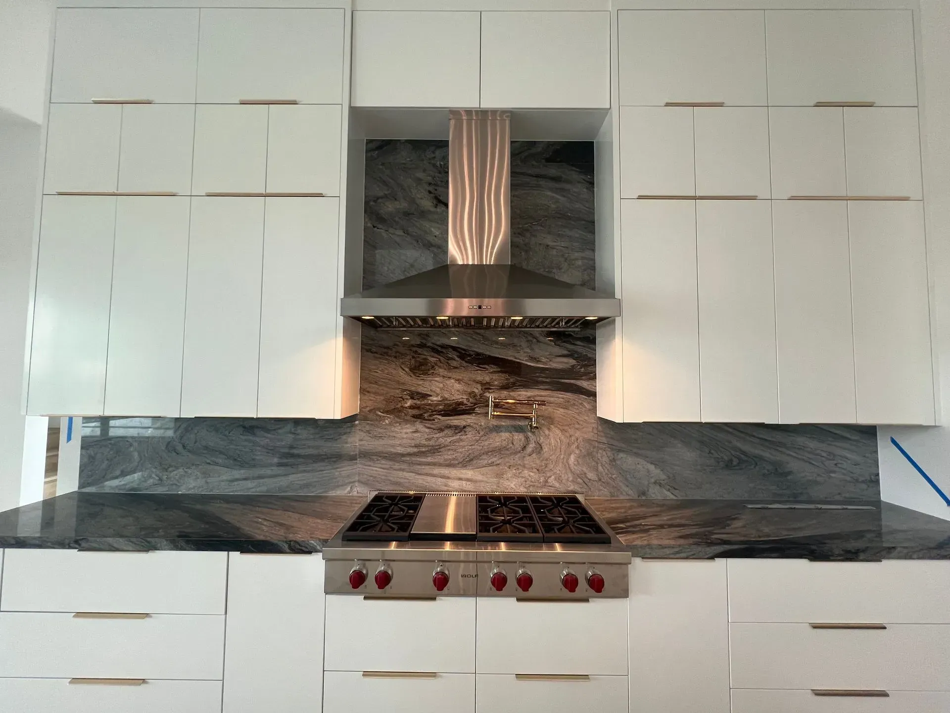A kitchen with white cabinets and a stove top oven
