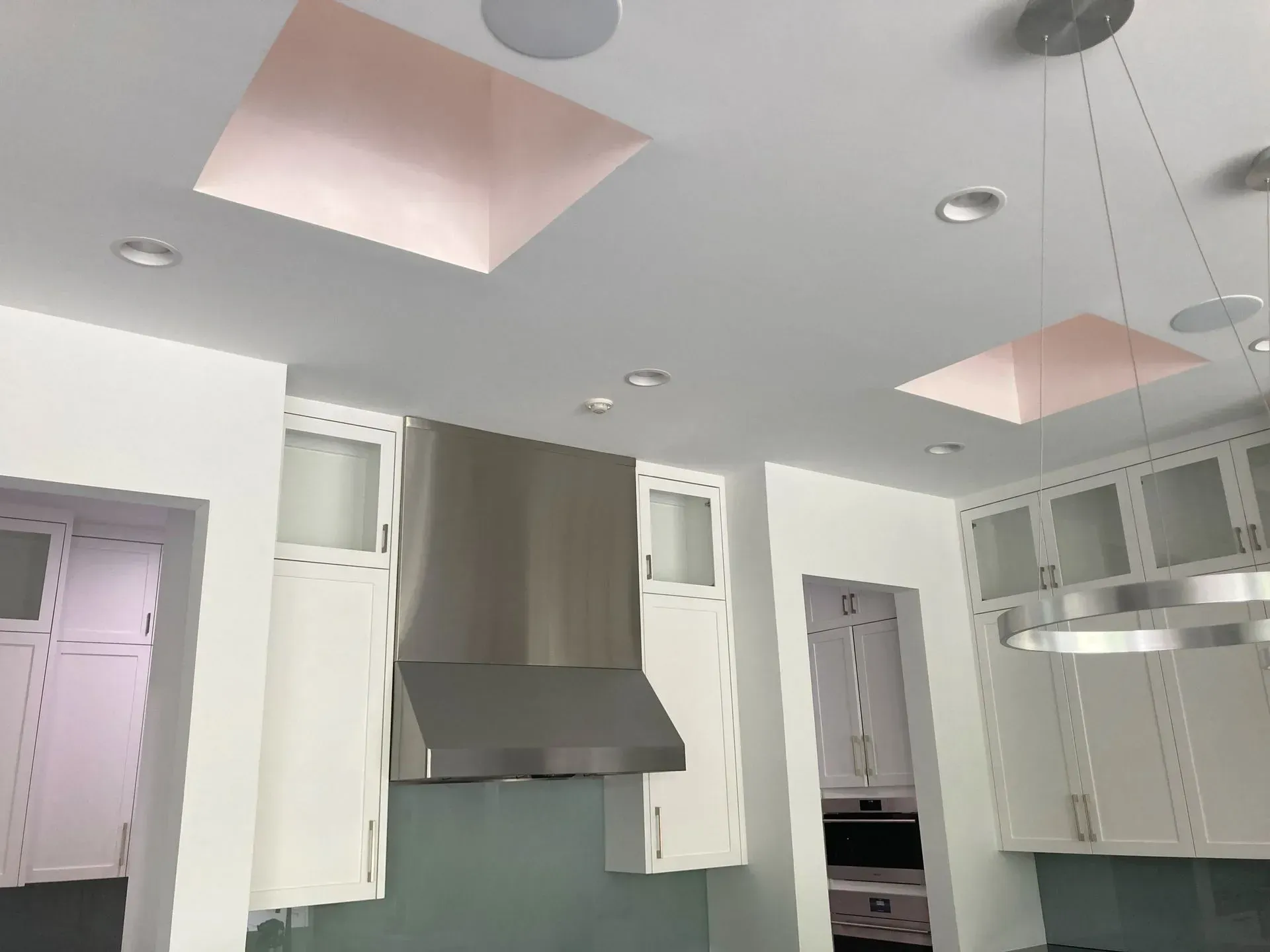 A kitchen with white cabinets and a stainless steel hood