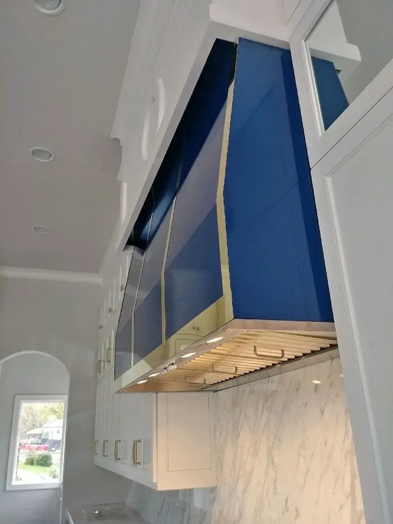 A kitchen with white cabinets and a blue hood