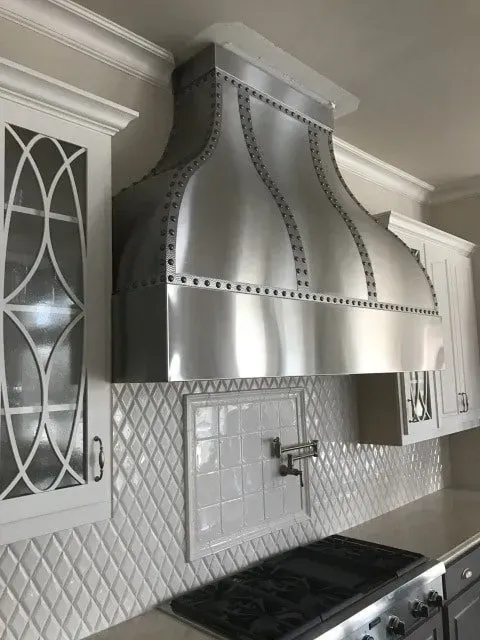 A kitchen with a stainless steel hood above the stove