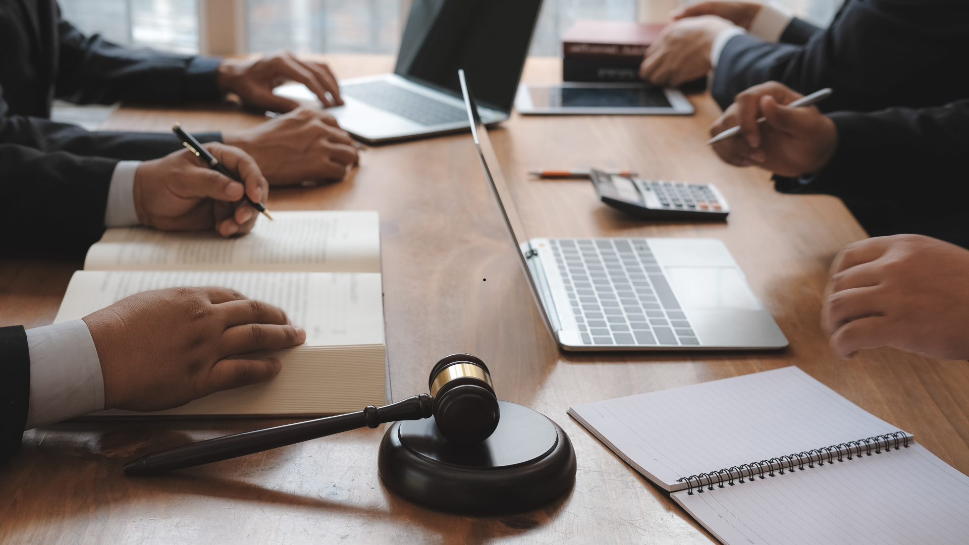 A group of people are sitting at a table with a laptop and a judge 's gavel.