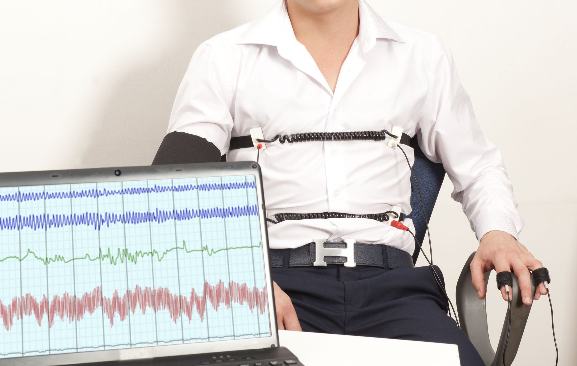 A man is sitting in front of a laptop with a heartbeat monitor attached to his chest.
