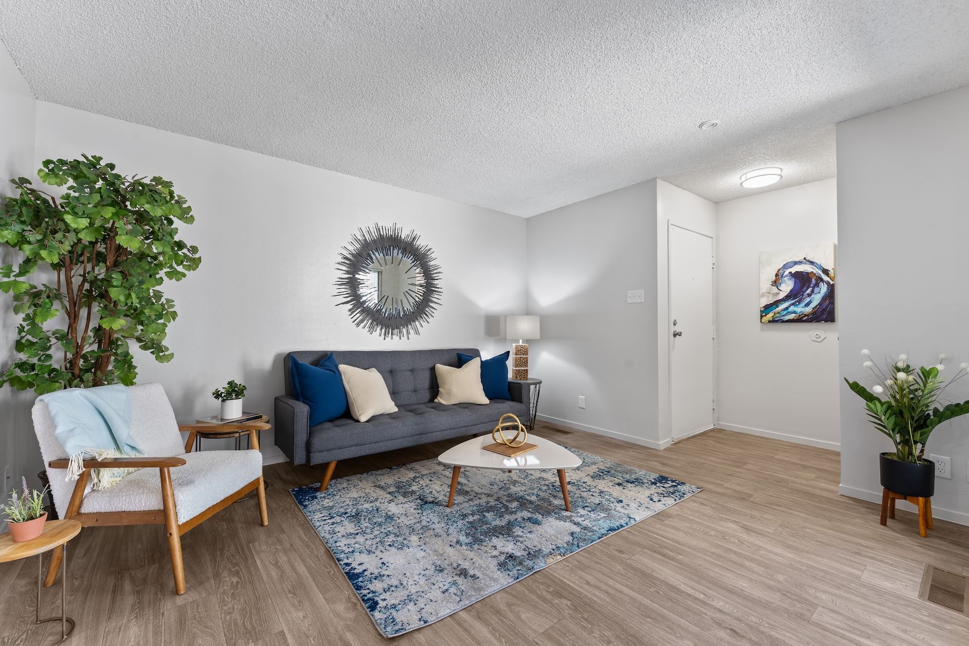Living room with blue couch, rug, and white walls.
