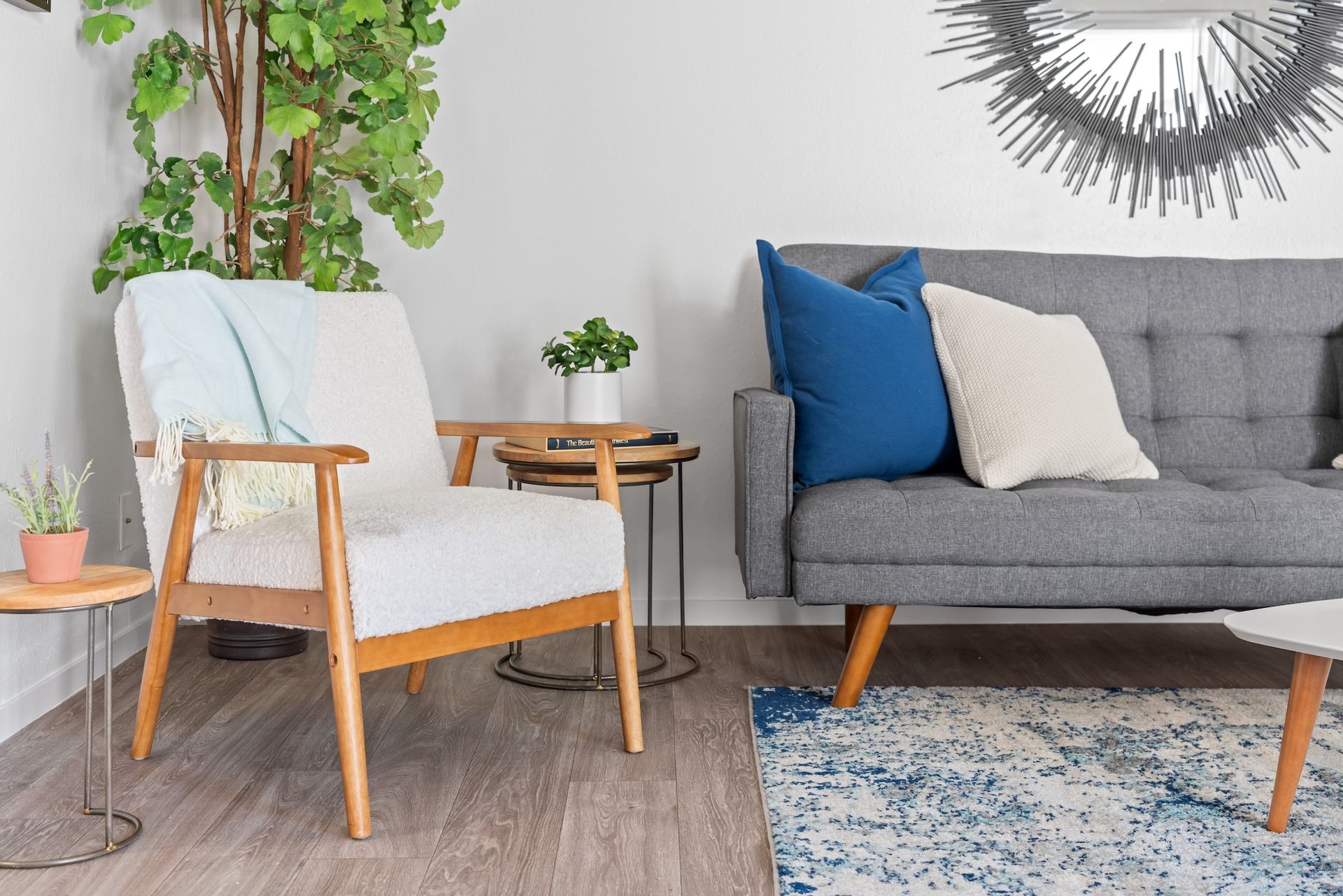 Living room with a gray sofa, white armchair, and blue rug.