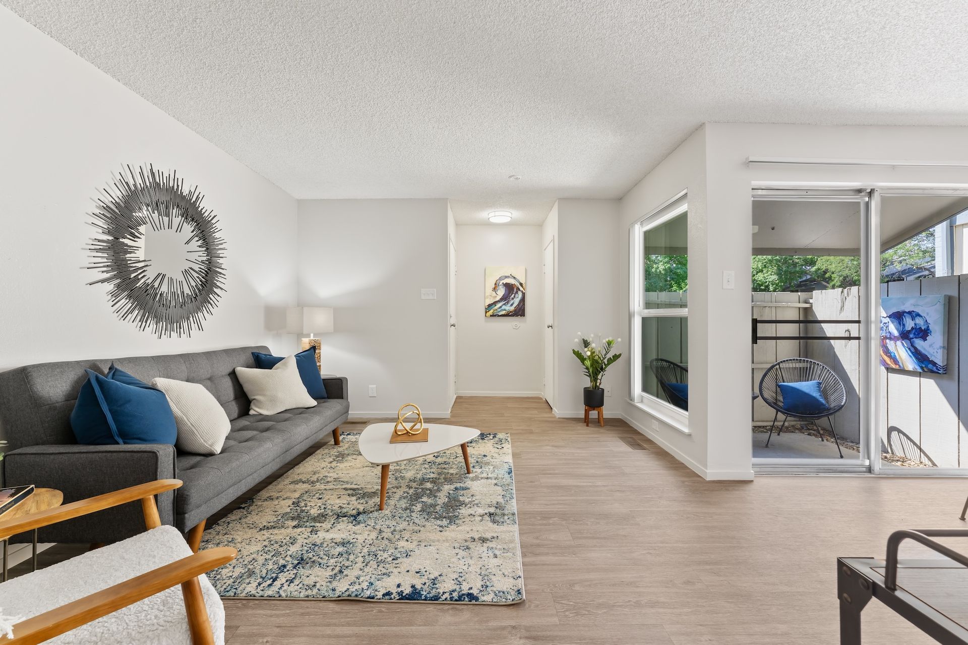 Living room with gray couch, rug, coffee table, and sliding door to balcony.