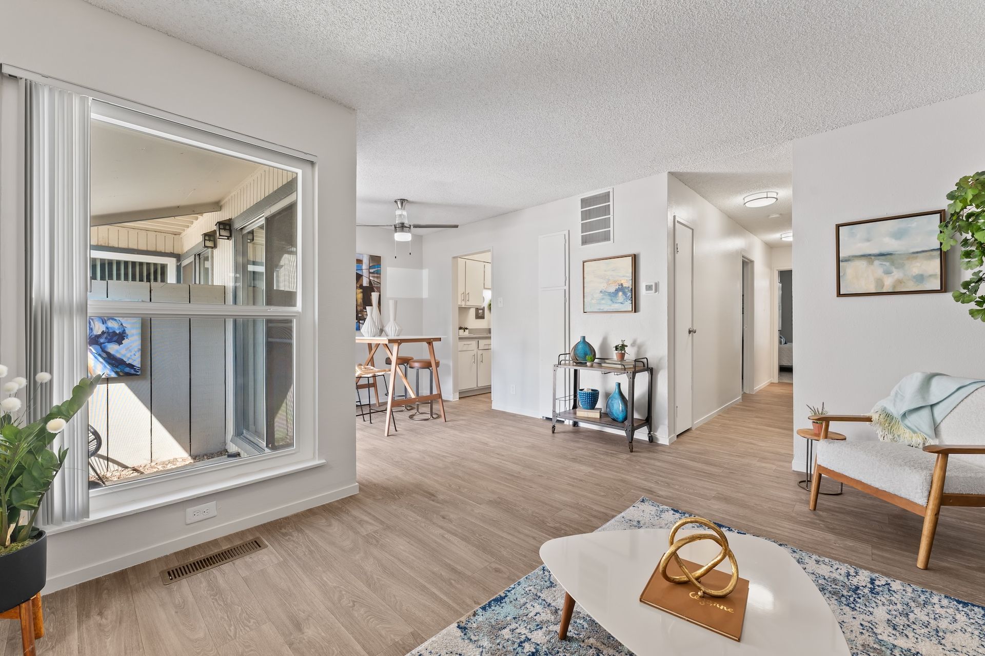 Bright living room with window, light wood floors, white walls, and decor.