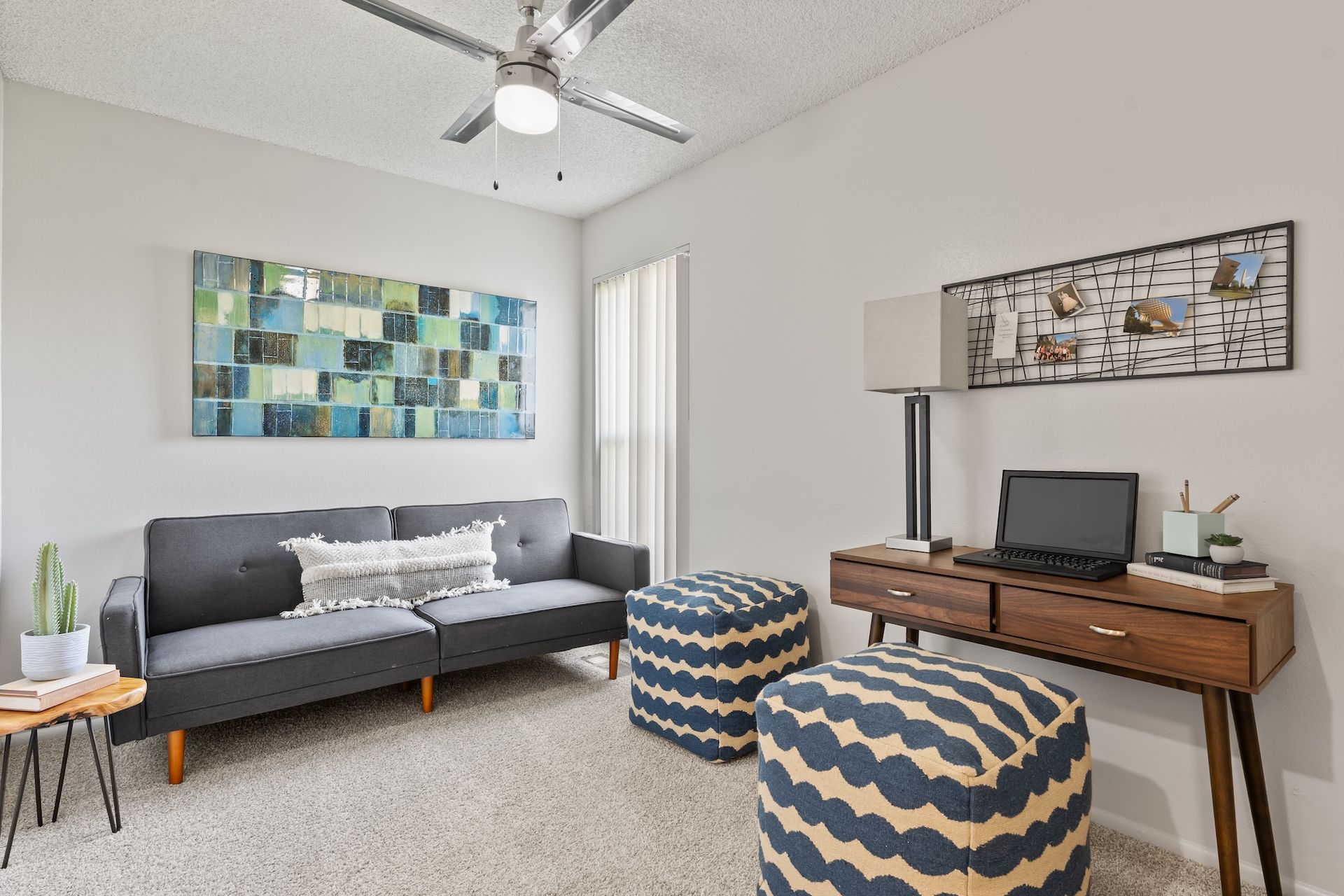 A room with a sofa, desk, and ottoman. Modern decor in shades of blue and brown.