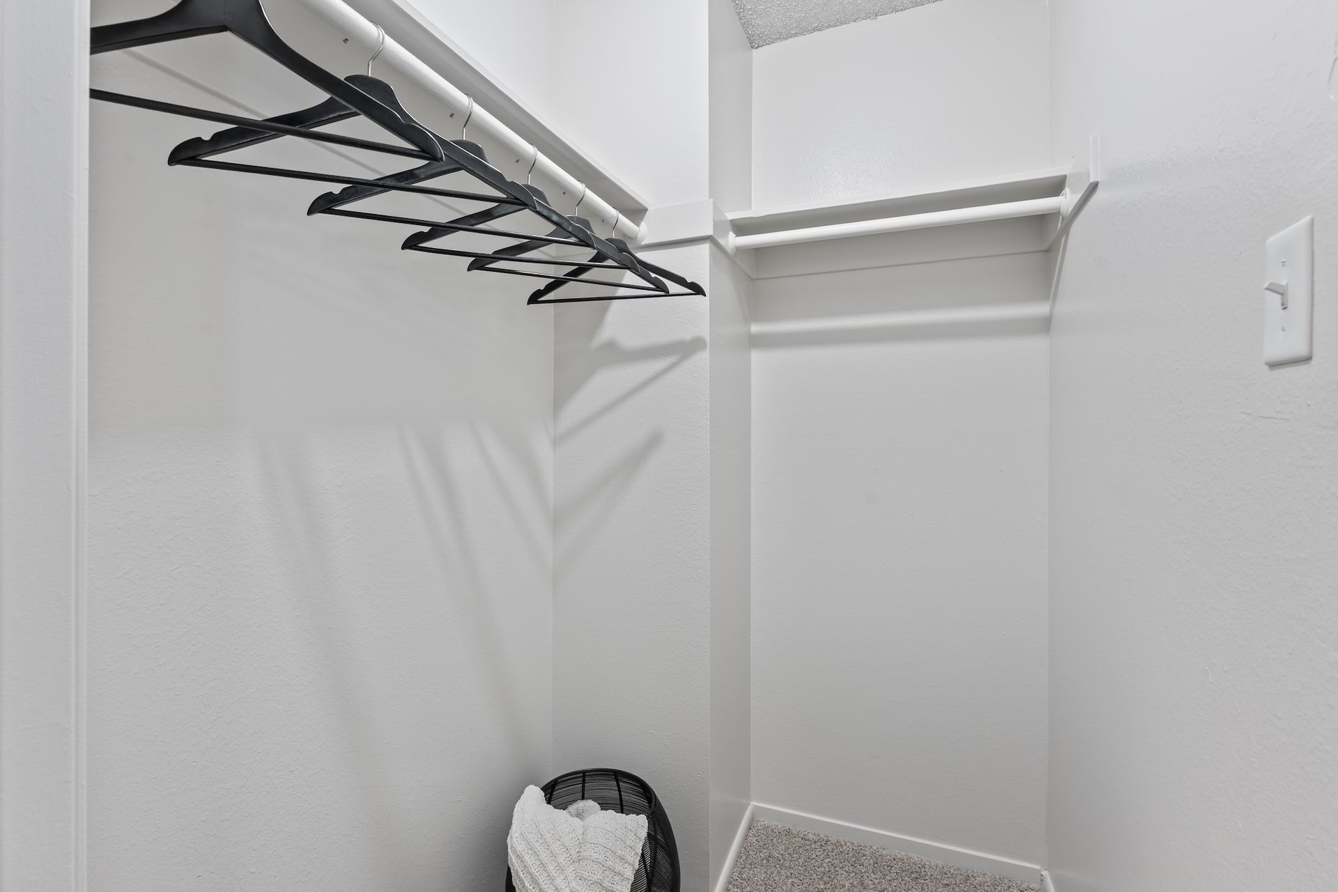 Empty walk-in closet with white walls, a top shelf, and a clothes rod with hangers.