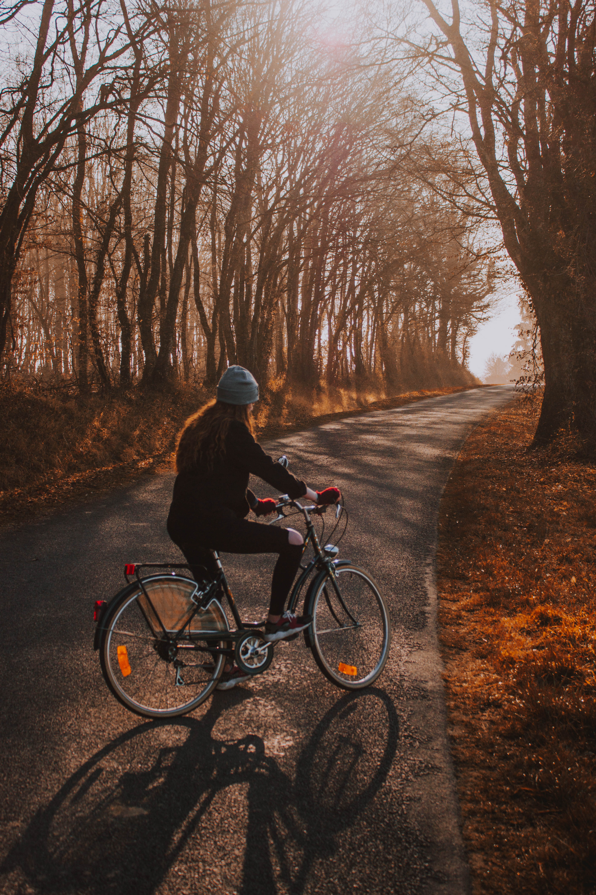 A woman is riding a bike down a road in the woods.