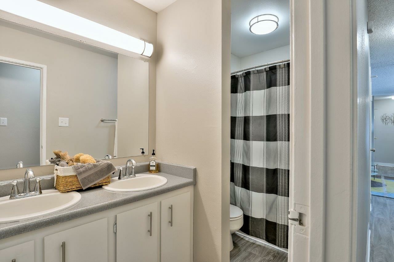 A bathroom with two sinks , a toilet , and a shower curtain The Park at Idlewild. 