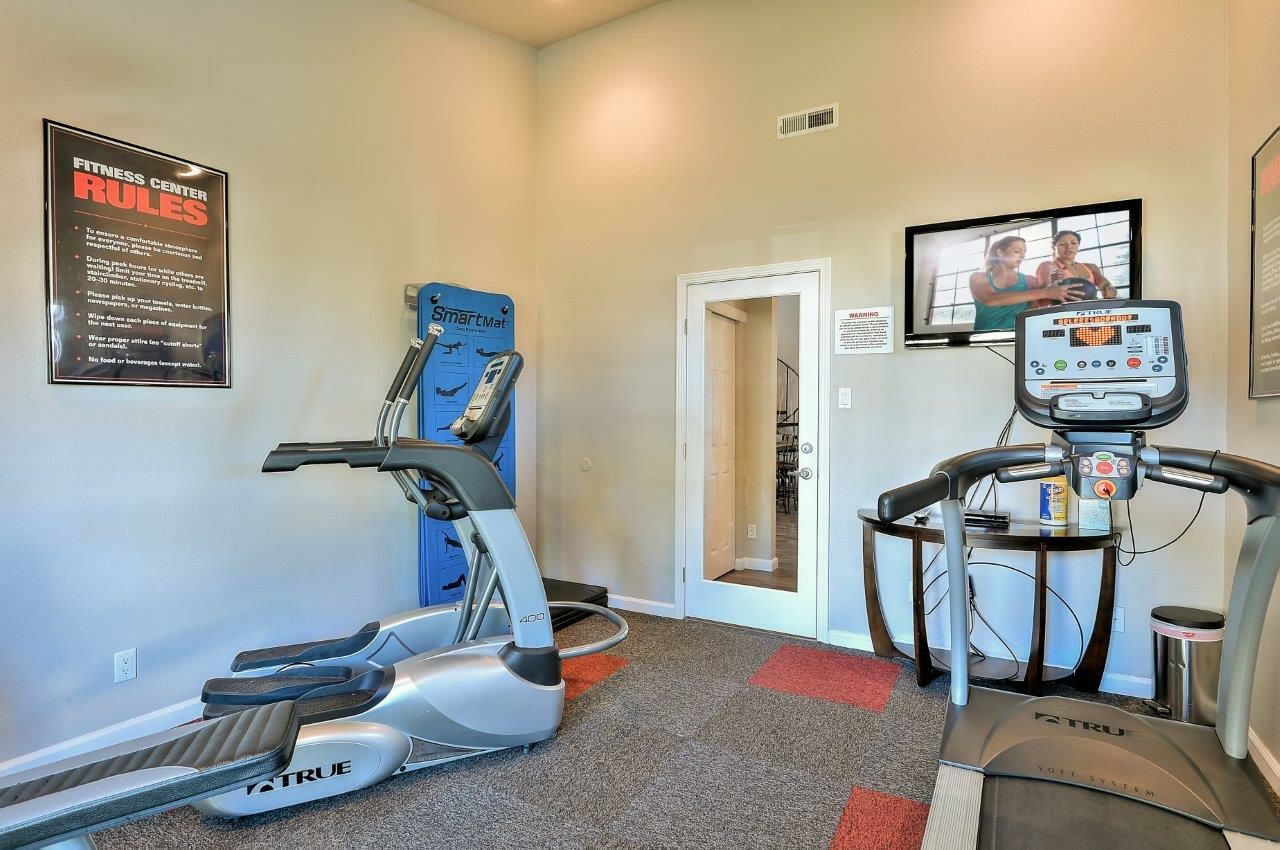 A gym with treadmills , ellipticals , and a television The Park at Idlewild. 