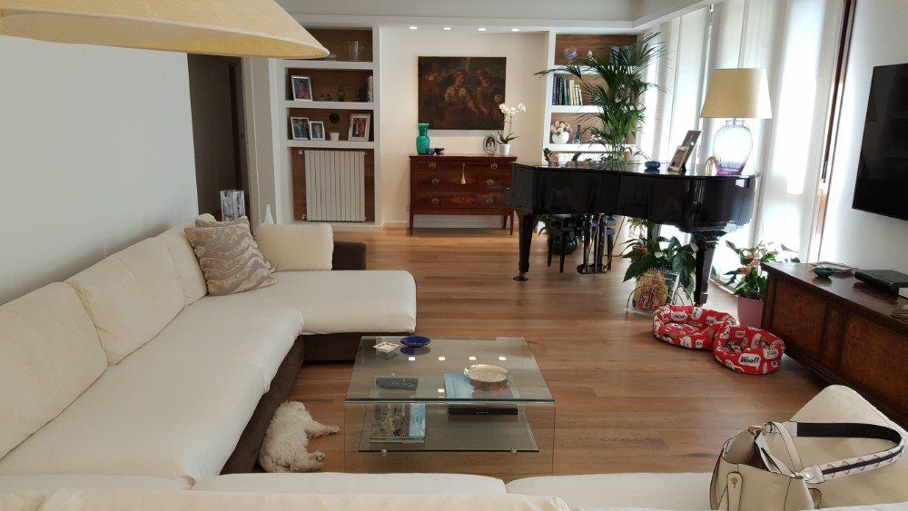 soggiorno con parquet e divano in pelle bianco