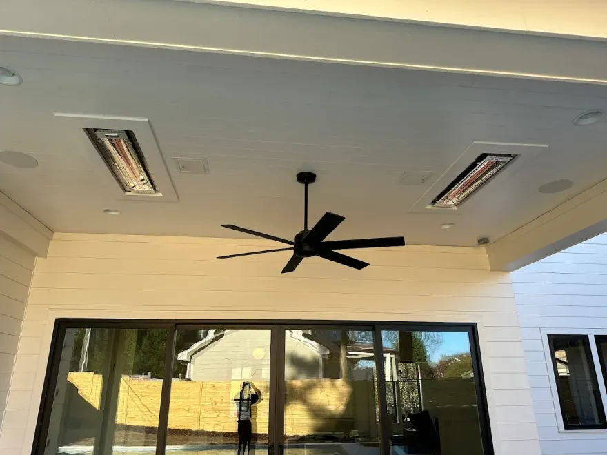 Outdoor patio with heaters, ceiling fan, and sliding glass doors.
