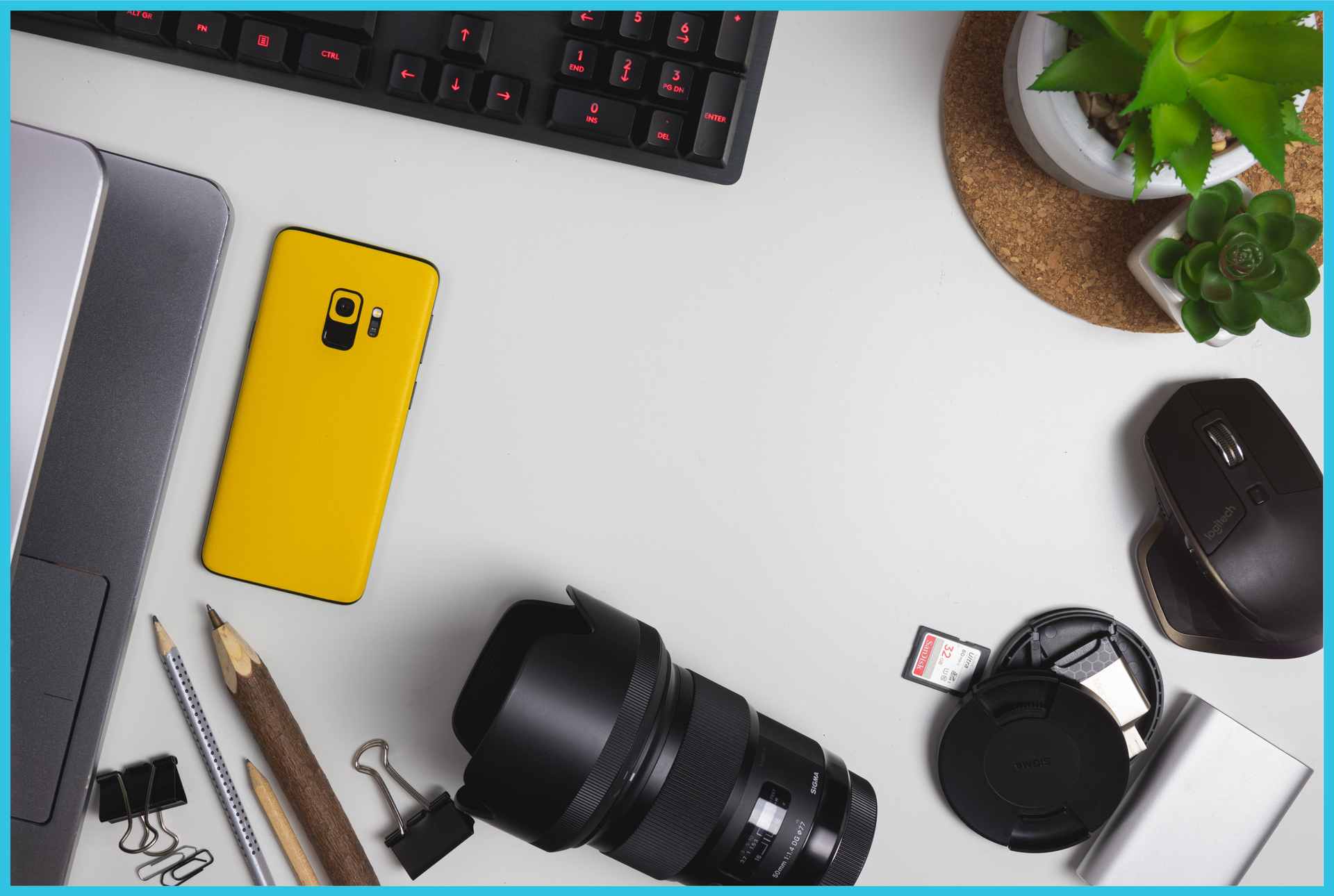 A desk with a camera lens a cell phone and a keyboard