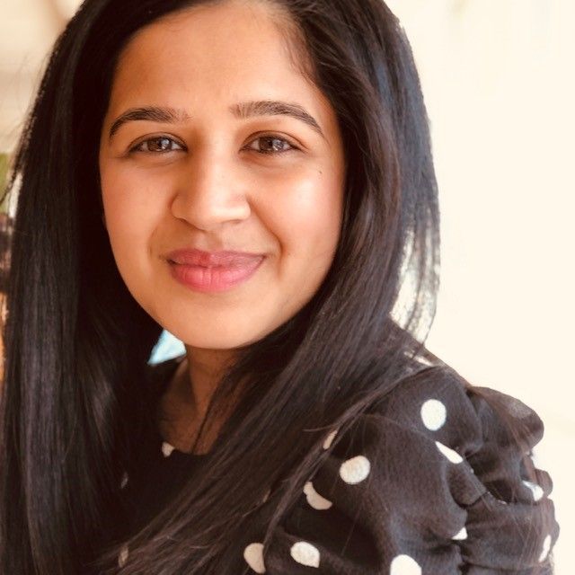 A woman wearing a black and white polka dot shirt smiles for the camera