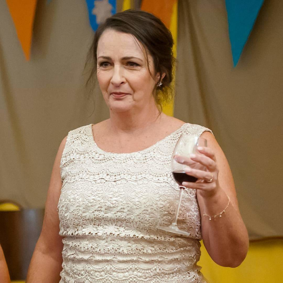 A woman in a white dress is holding a glass of wine