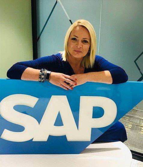A woman leans on a blue sign that says sap