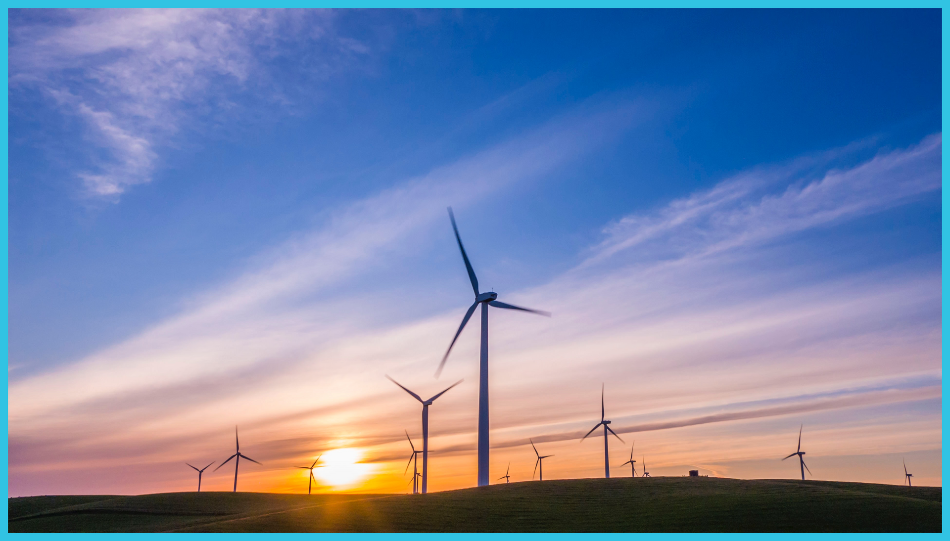 A row of wind turbines on a hill at sunset