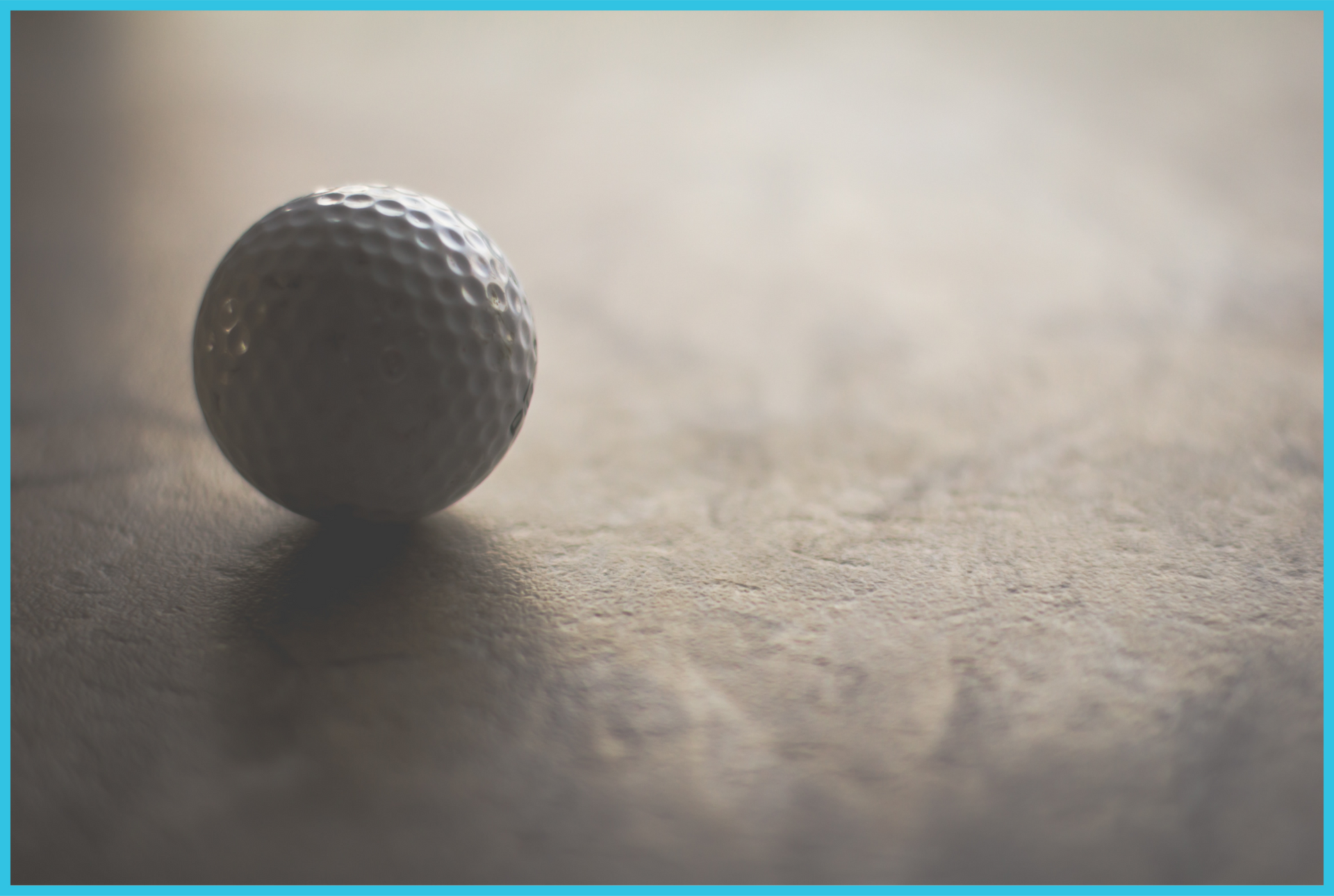 A golf ball is sitting on a concrete surface.