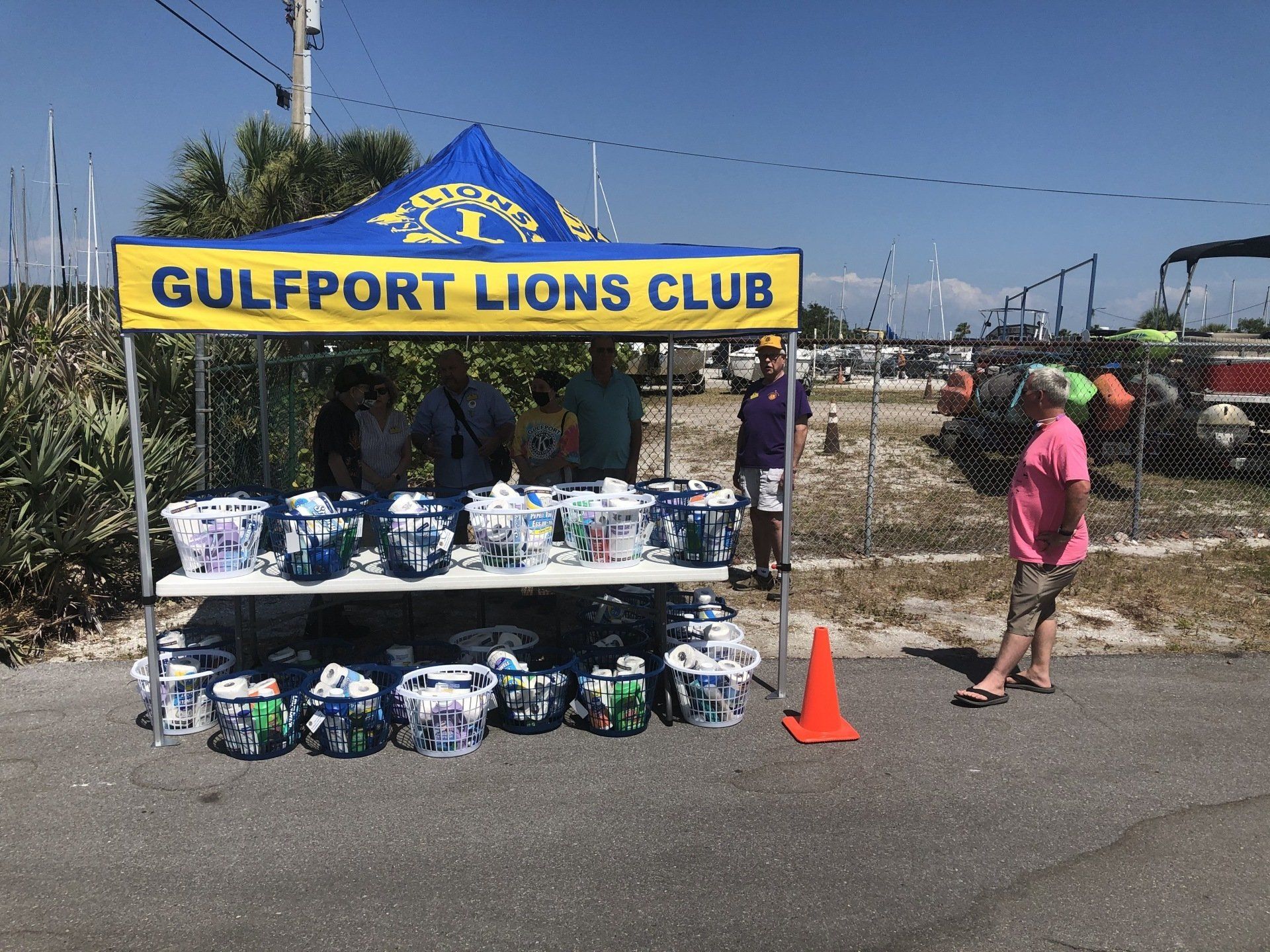 Gulfport Lions Club booth selling items. People stand behind and in front of a table.